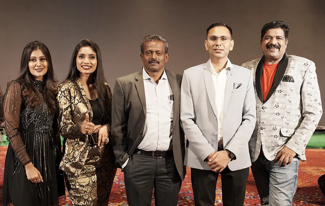 Five people in evening wear posing together on stage at the Dealers Meet.