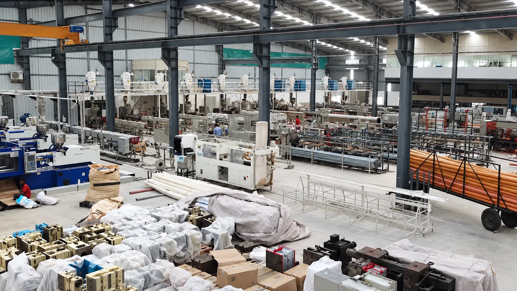 The Vahini production hall in Tumakuru: extrusion lines, moulding machines and finished pipe on the floor.