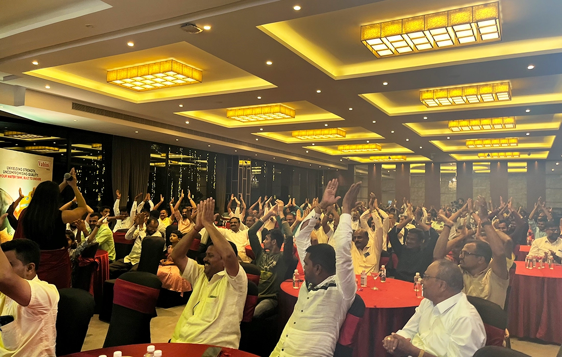 Dealers in a banquet hall cheering with raised arms during the evening's entertainment.